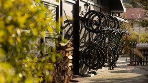 A building with a garage door, a bicycle rack with multiple bicycles, and a stack of firewood. - Sherwood Queenstown (Queenstown)