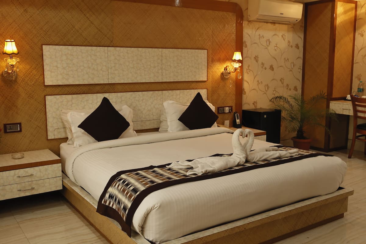 Una habitación de hotel con una cama grande, dos mesitas de noche, un escritorio y una silla.