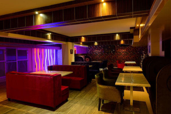 A modern lounge area with red and black seating, a flat-screen TV, and ambient lighting.