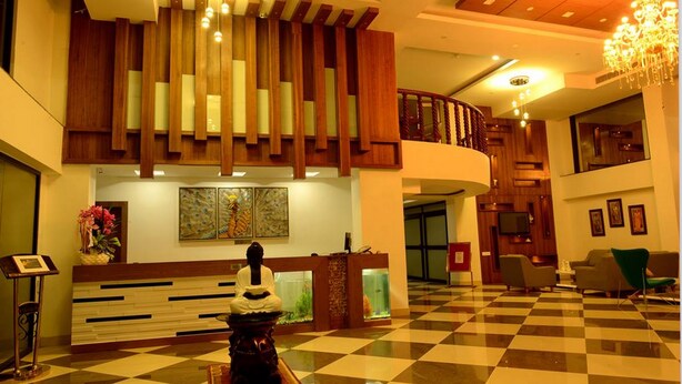 Un vestíbulo con piso a cuadros, una recepción, una estatua y un candelabro.