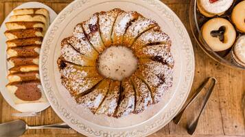 Un piatto dessert con diversi dolci e una torta centrale spolverata di zucchero a velo.