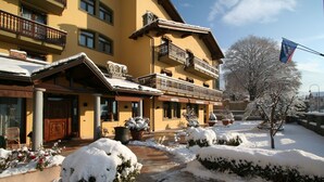 Un hotel con entrada nevada, balcones y una bandera.