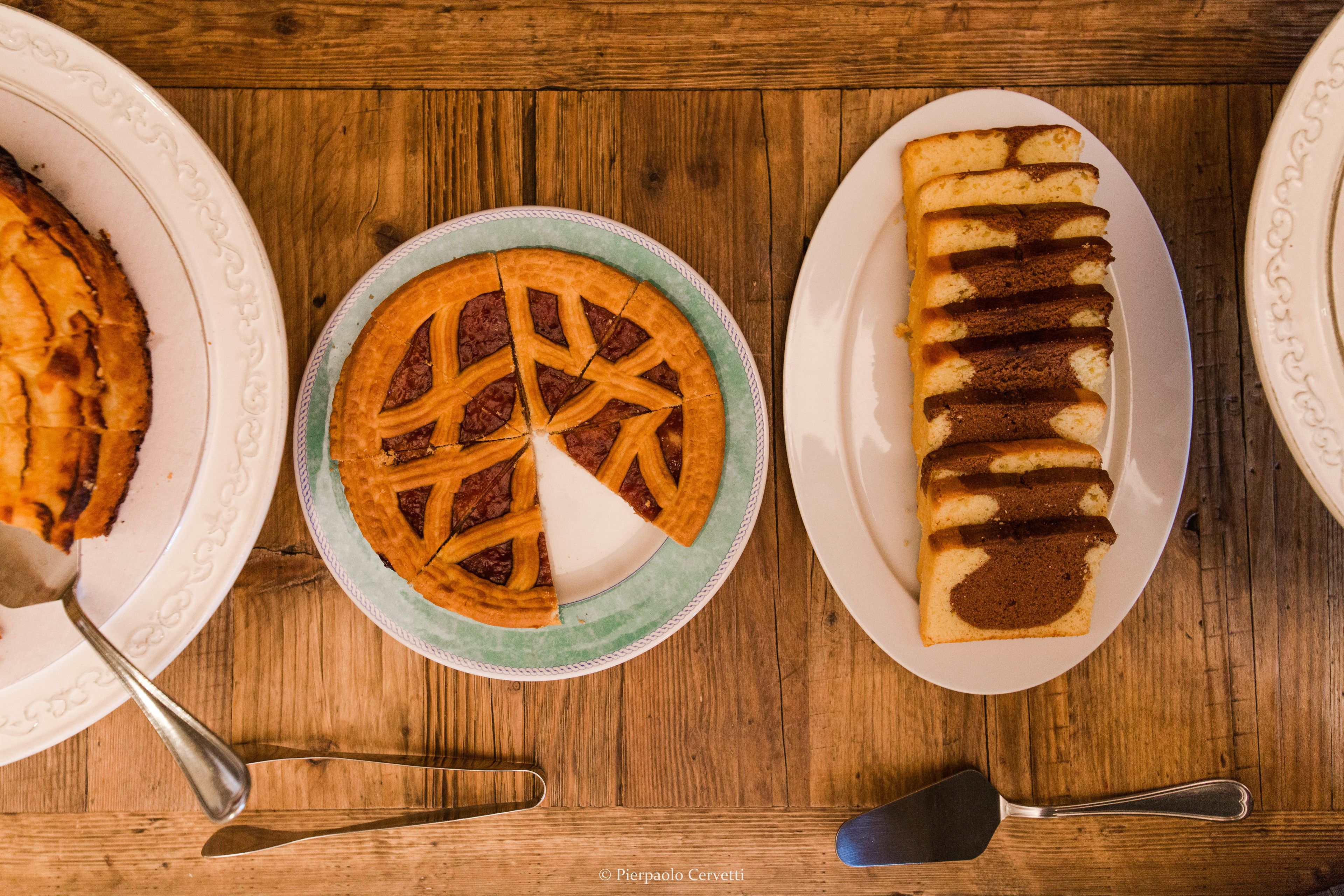 Ein Holztisch mit drei Tellern Essen: ein Kuchen, eine Torte und Brot.