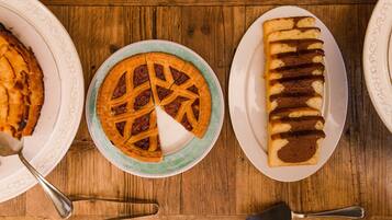 Ein Holztisch mit drei Tellern Essen: ein Kuchen, eine Torte und Brot.