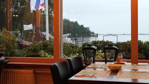 A table set with a bowl, plates, and cutlery, overlooking a body of water with a flag in the background. - Hotel Restaurant Ie-Sicht (Oudega)