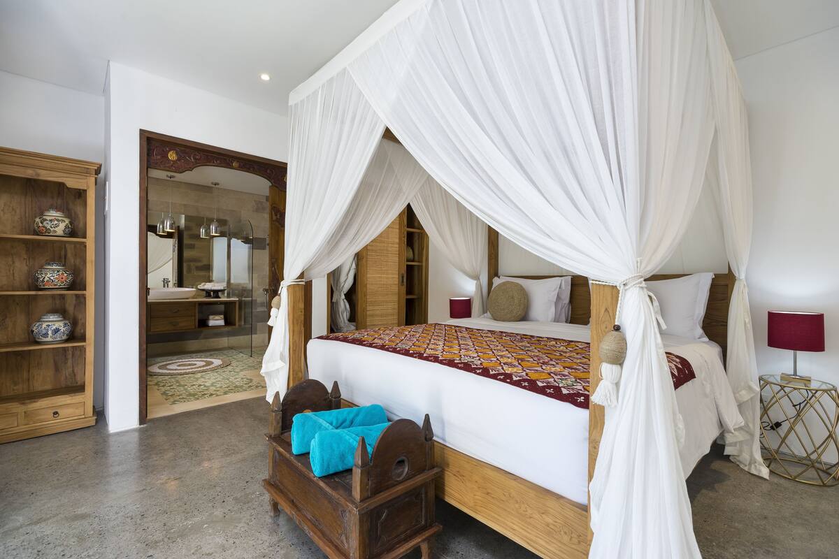 A bedroom with a four-poster bed, wooden furniture, and a traditional decor style.