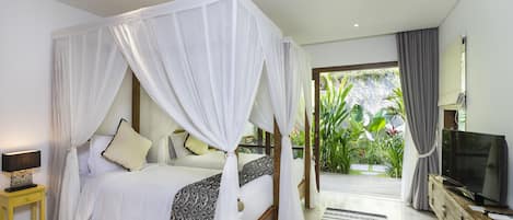 Un dormitorio con cama con dosel, televisión y vista a un jardín exuberante.