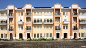 A multi-story hotel with balconies, a brick-paved courtyard, and a clear blue sky. - The Gilgal Guest House (Lekki)