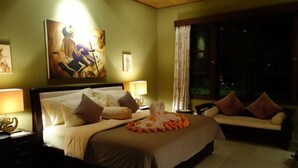 A hotel room with a large bed, a sofa, a nightstand, and a painting on the wall. - Villa Sidemen (Sidemen)