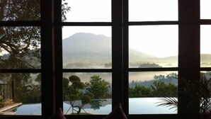 A room with a large window overlooking a mountainous landscape and a body of water. - Villa Sidemen (Sidemen)