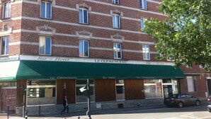 A multi-story brick building with a green awning labeled "Bar - Hotel Le Clémenceau."