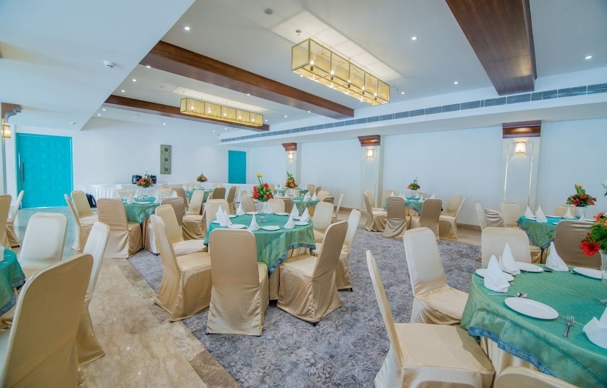 A conference room with round tables, beige chairs, and green tablecloths.