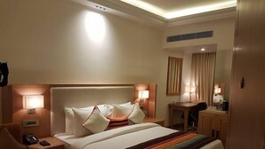 A hotel room with a large bed, two bedside lamps, a desk with a chair, and a mirror.