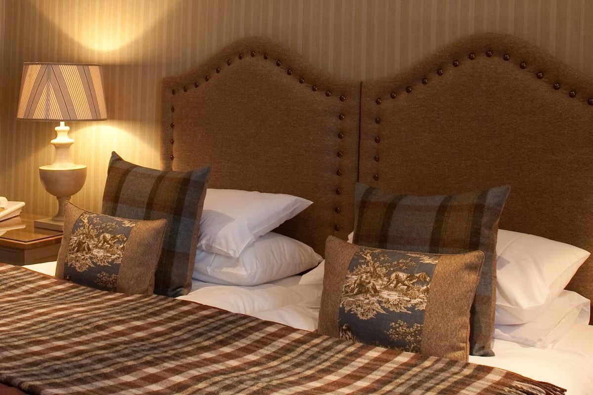 A hotel room with a large bed, two bedside tables, and two lamps.