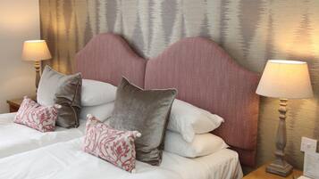A hotel room with a large bed, multiple pillows, two bedside lamps, and a textured wall behind the bed.