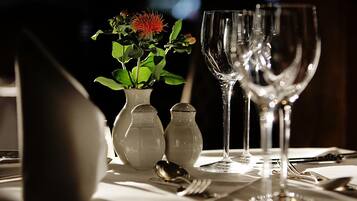 A dining table with a vase of flowers, salt and pepper shakers, and a wine glass.