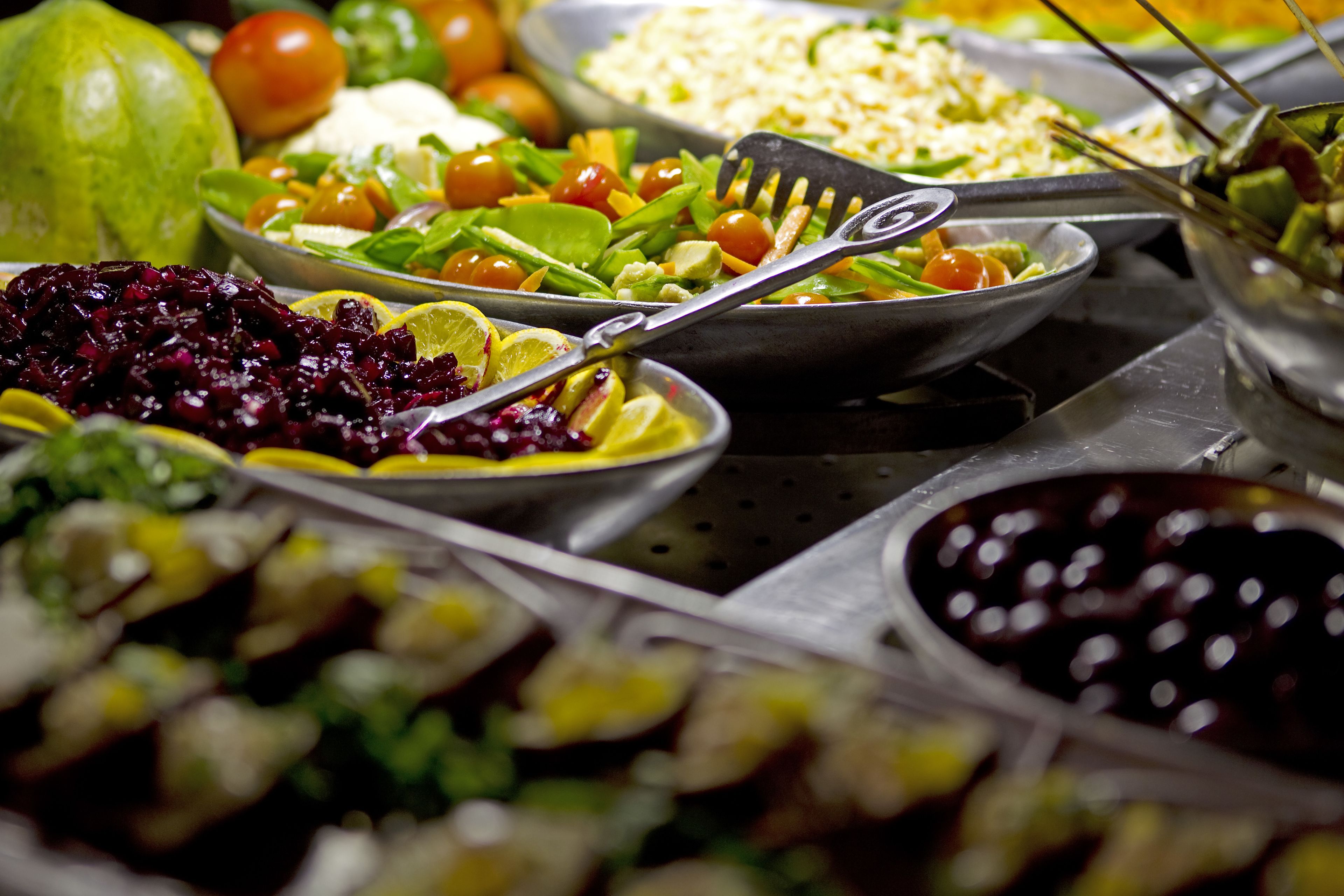 A buffet with various dishes including salads, fruits, and vegetables.