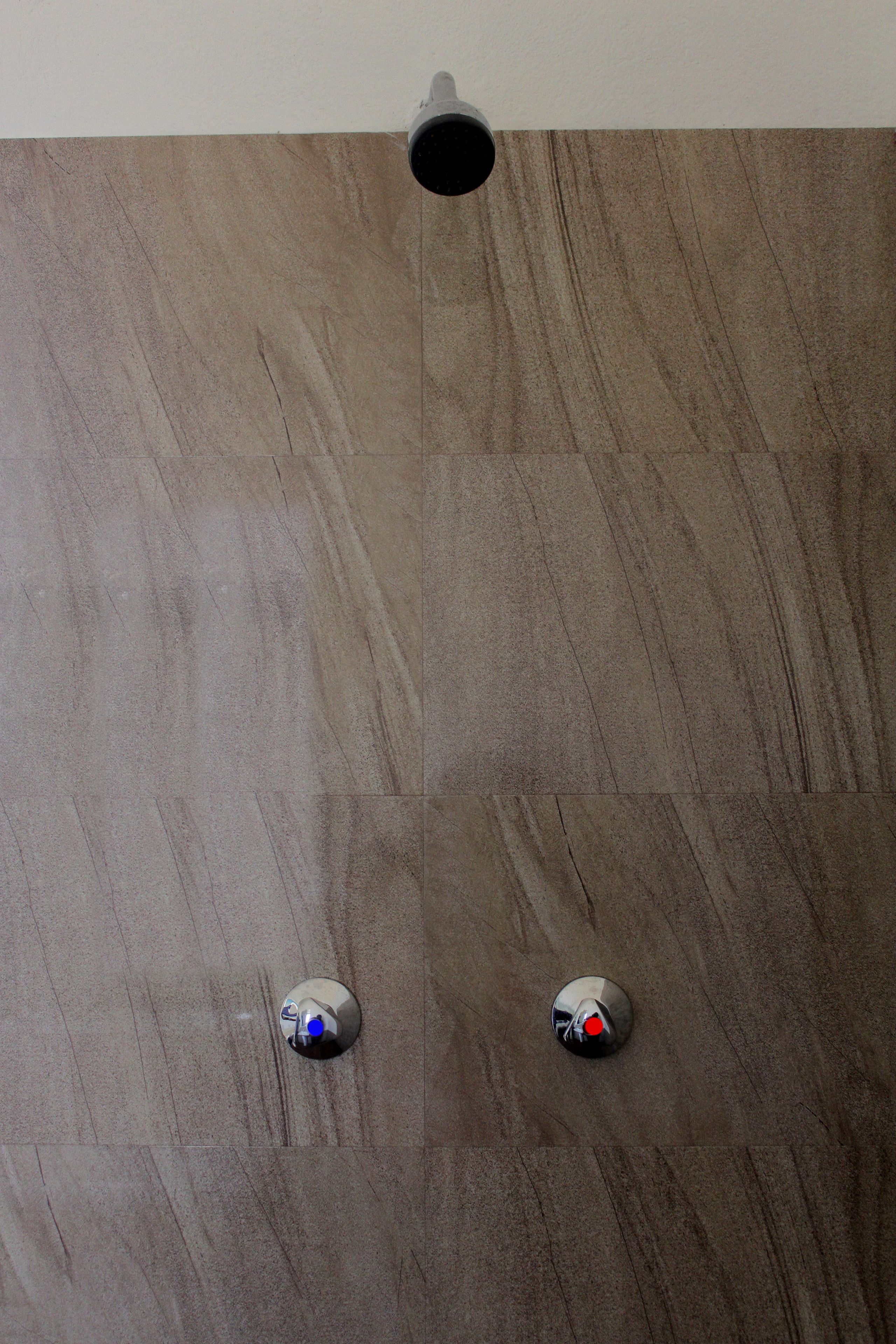A bathroom with a wooden floor and two metallic fixtures, one with a blue light and the other with a red light.