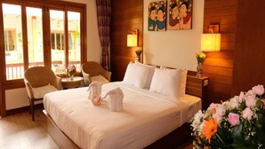 A hotel room with a large bed, two chairs, a small table, and a view of the outdoors through a sliding door. - Vieng Mantra (Chiang Mai)