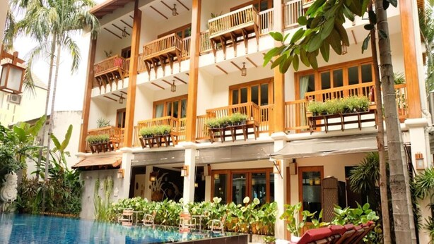 A hotel with a pool, multiple balconies with wooden railings, and lush greenery. - Vieng Mantra (Chiang Mai)
