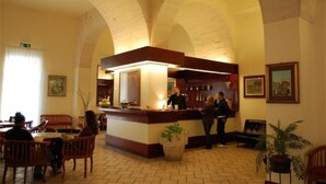 A bar area with a counter, seating, and a tiled floor. - Hotel Miramare (Otranto)