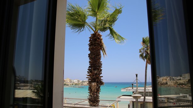 A balcony with a view of a beach and palm trees. - Hotel Miramare (Otranto)