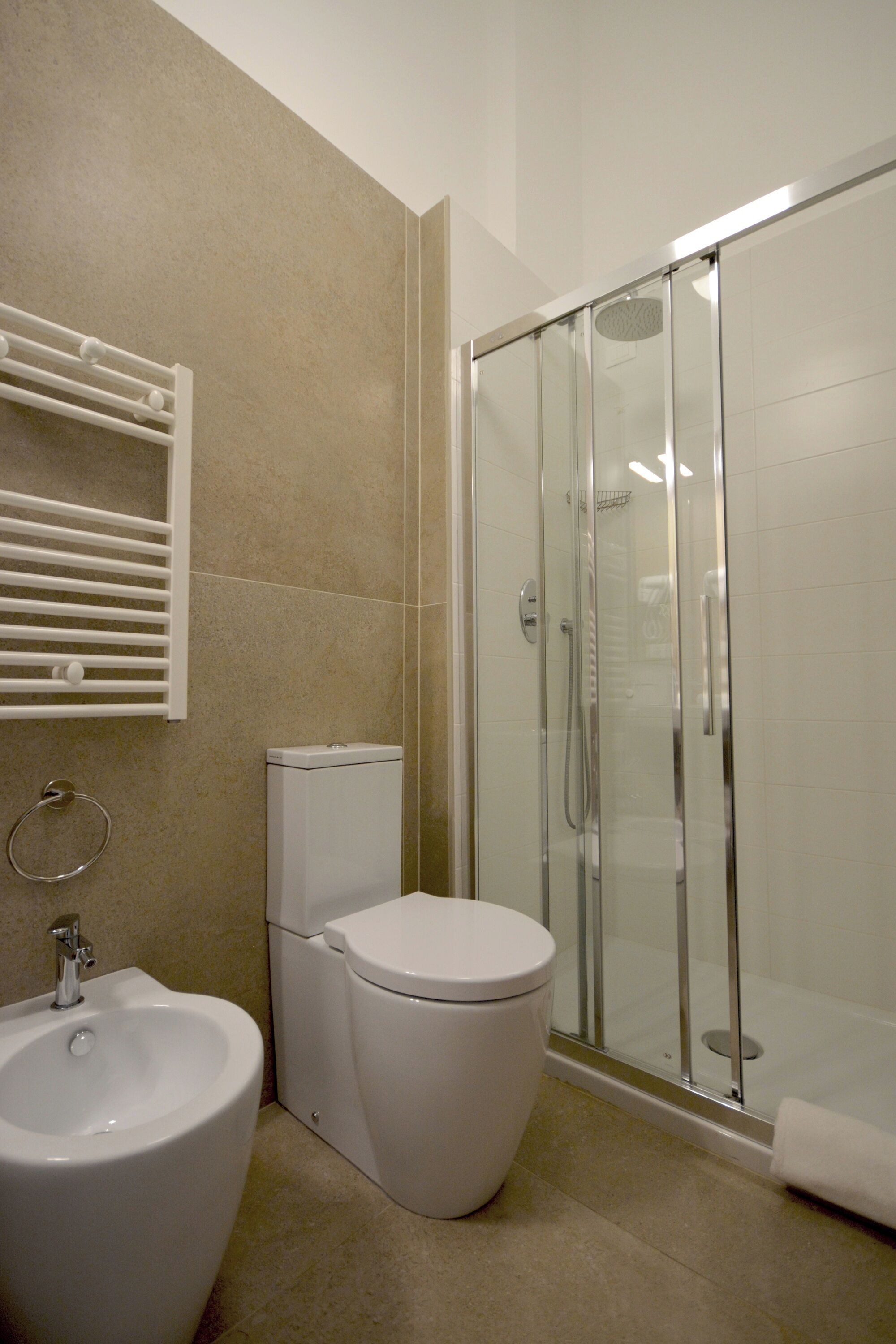 A bathroom with a toilet, bidet, and a glass-enclosed shower area.
