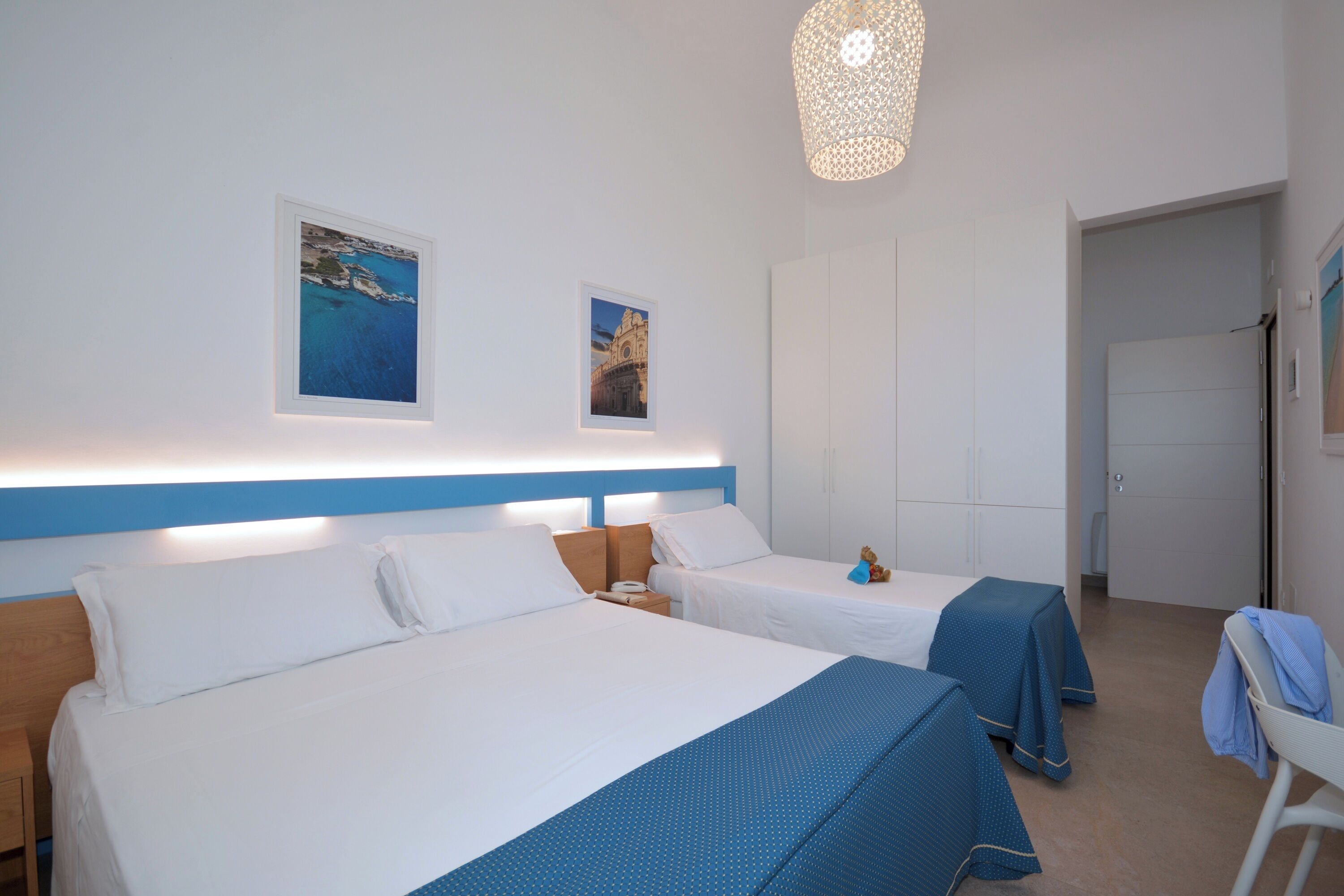 Una camera d'albergo con due letti, una grande finestra e un lampadario.