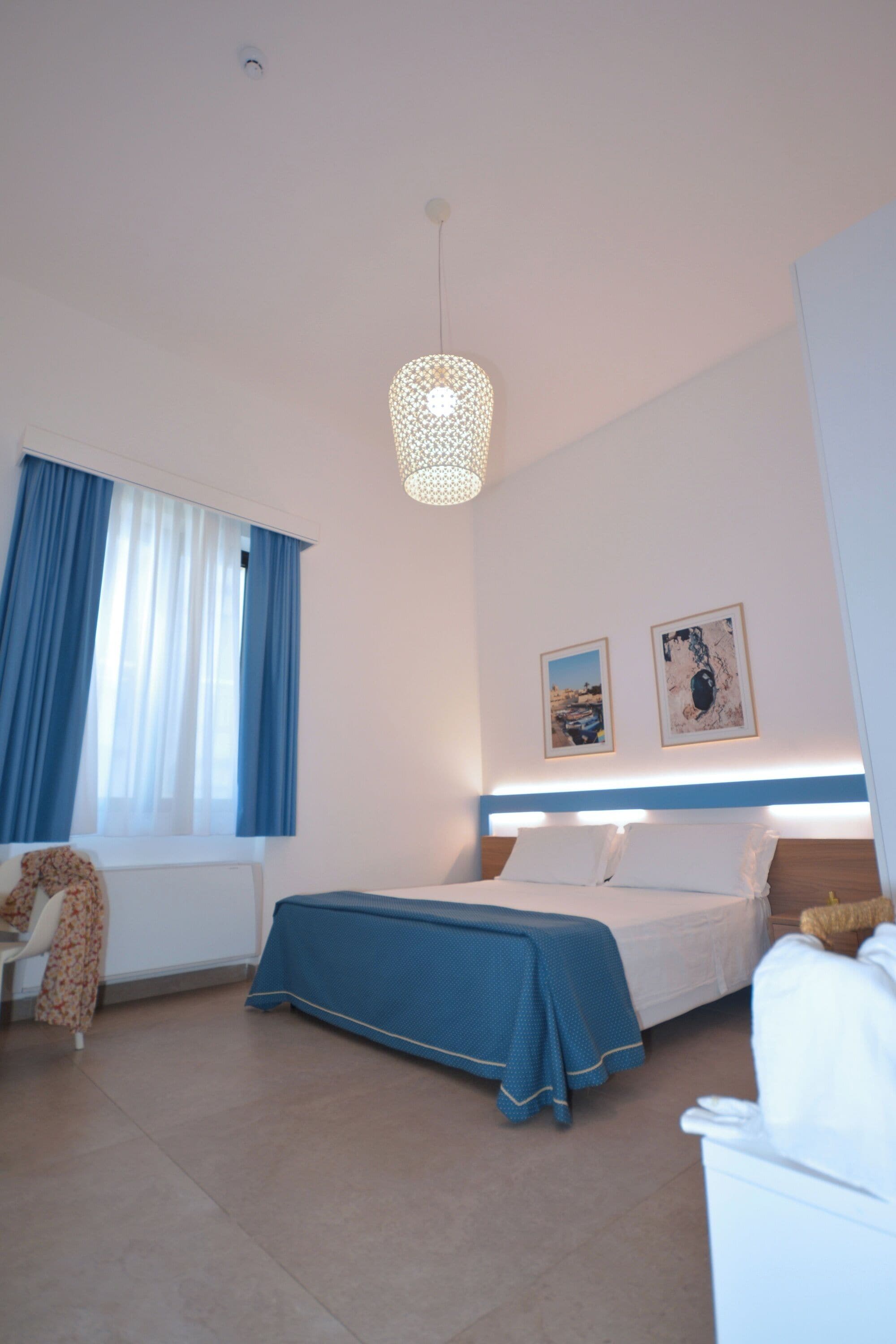 A bedroom with a bed, a chair, a table, and a window with curtains.
