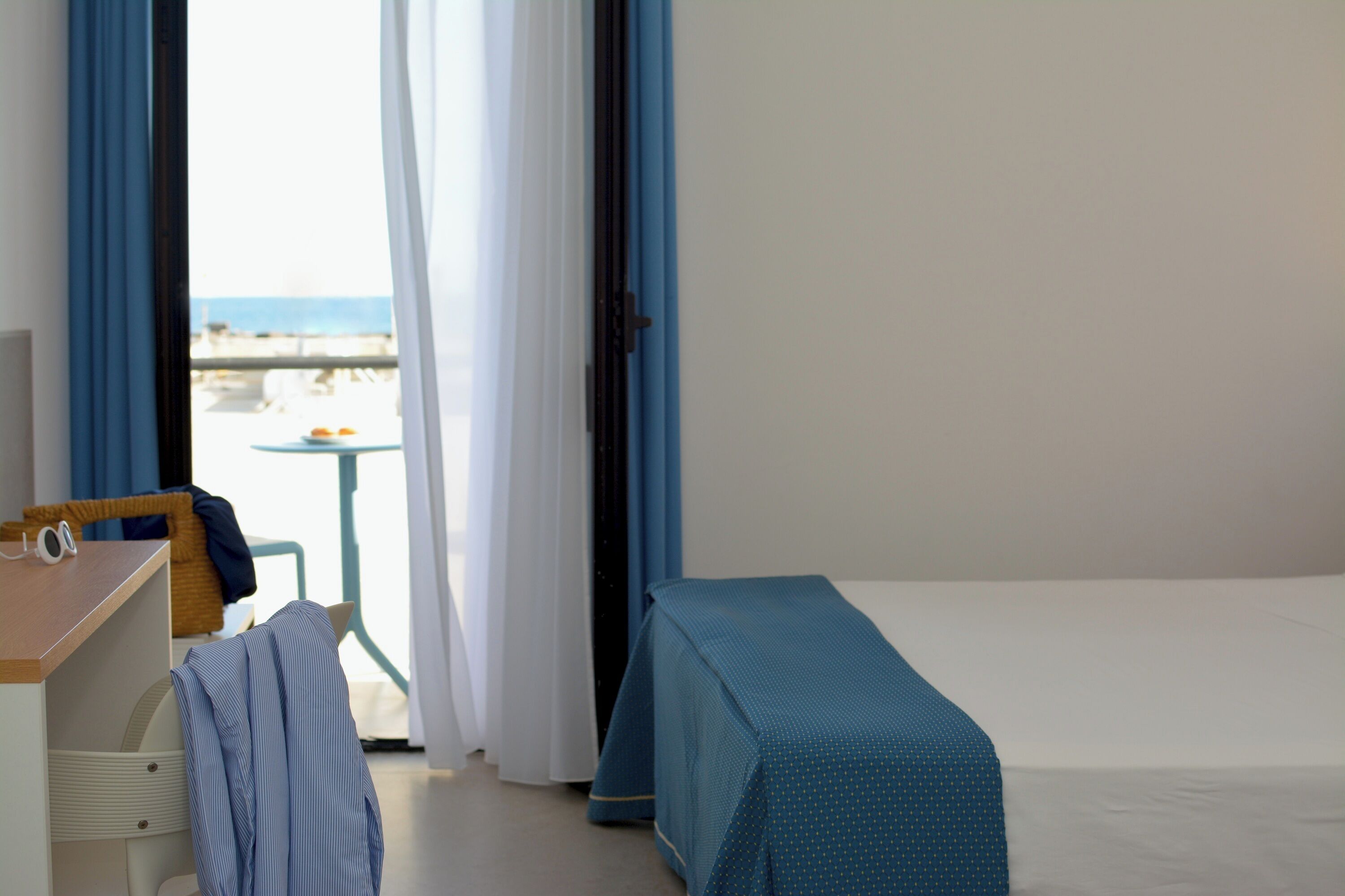 Una habitación de hotel con una cama, un escritorio, una silla y vista a la playa.