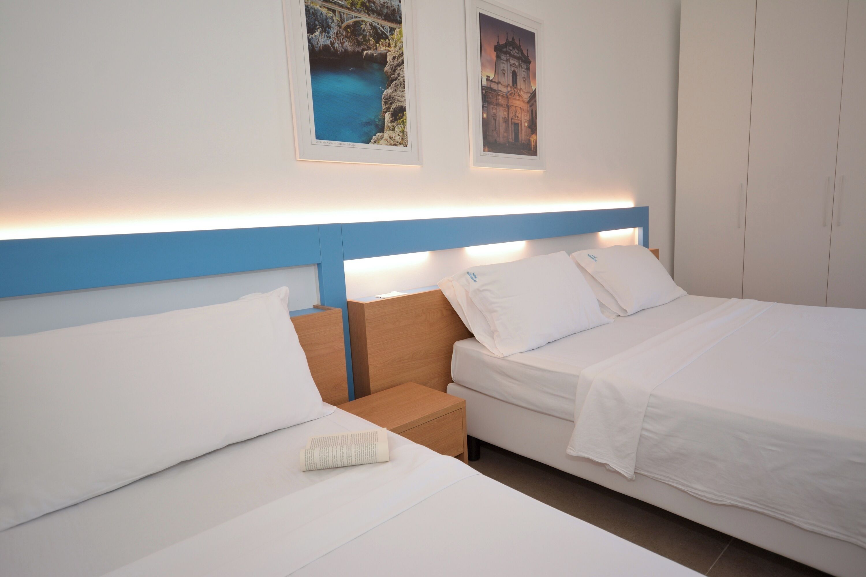 Una habitación de hotel con dos camas, una mesita de noche y un armario.