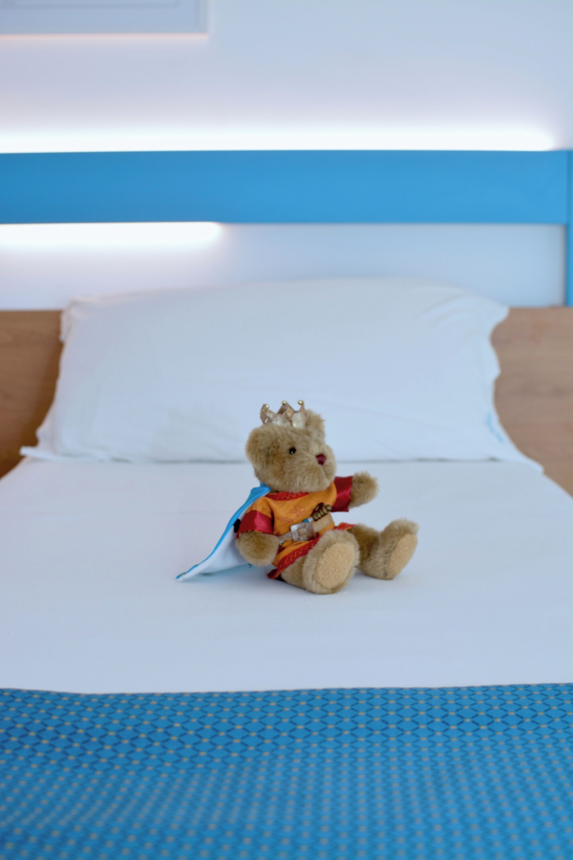 Een bed met een wit kussen en een blauw hoofdeinde.
