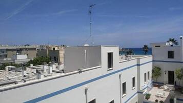 Una terraza en la azotea con vistas despejadas al mar, una antena parabólica y un edificio moderno con una franja azul.