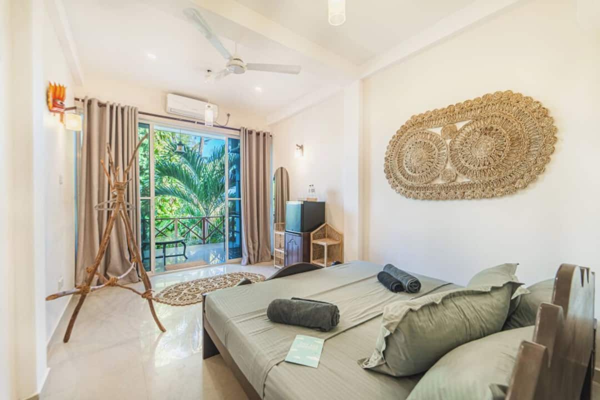 A modern hotel room with a bed, a television, a ceiling fan, and a balcony with curtains.