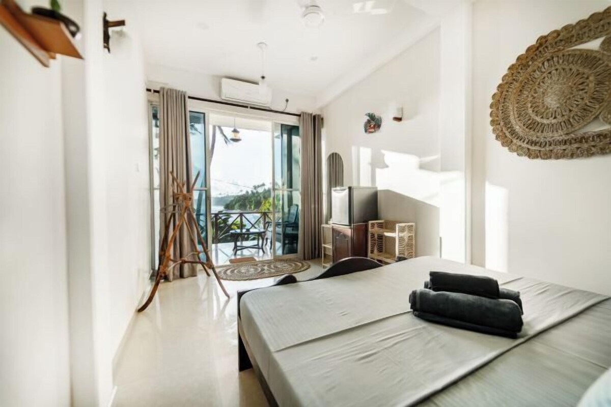 Une chambre d’hôtel moderne avec un grand lit, une télévision et un balcon offrant une vue agréable.