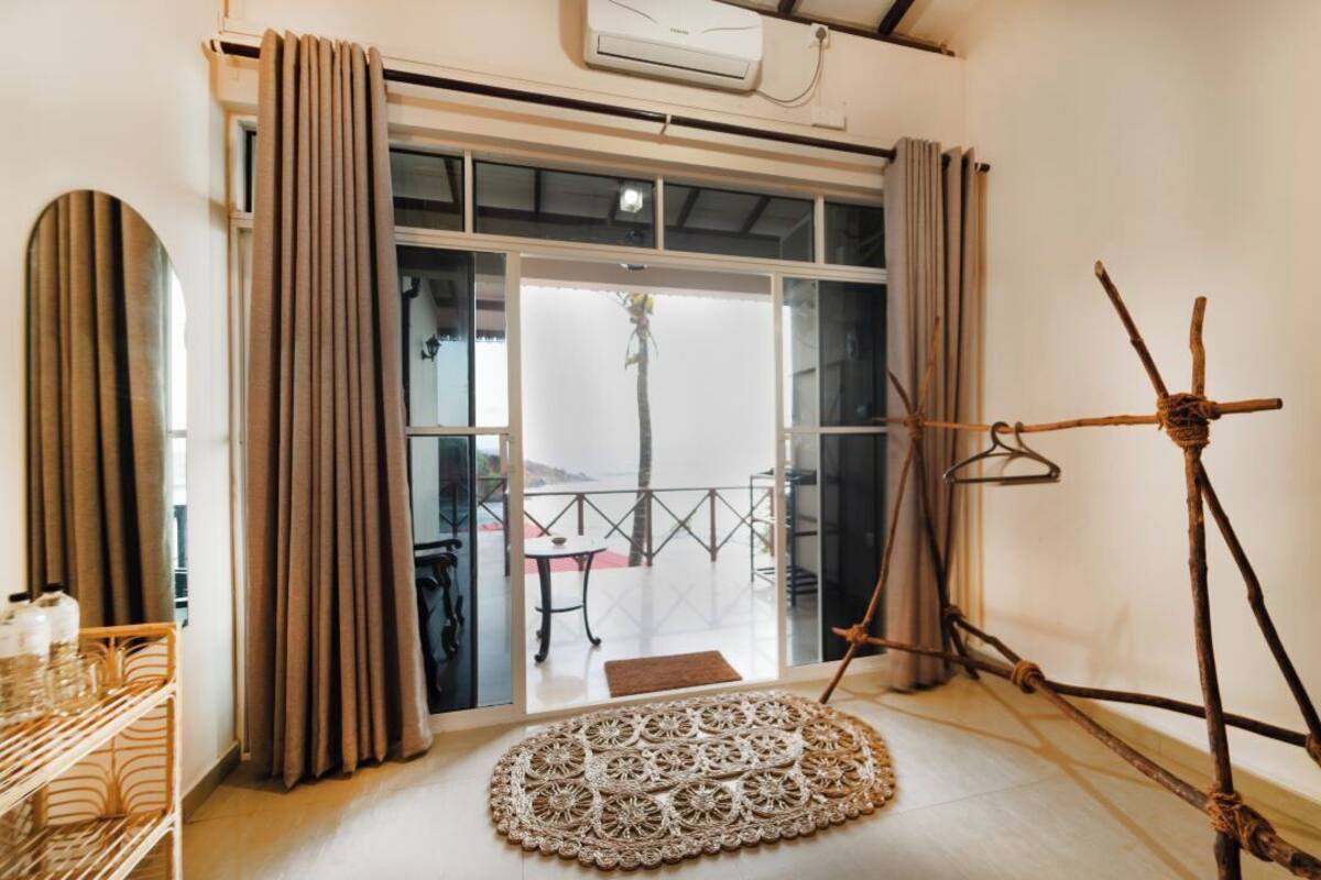 A room with a large sliding glass door leading to an outdoor area, a woven mat on the floor, and a rustic wooden structure.