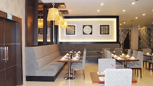 Un hall d’hôtel comprenant un espace salon avec des fauteuils et des tables, ainsi qu’un comptoir d’accueil.