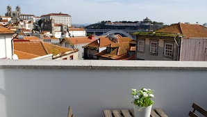 A terrace with a potted plant, wooden benches, and a view of historic buildings and a bridge. - Belos Aires Apartments (Porto)