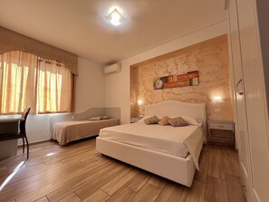 A bedroom with a large bed, a smaller bed, a desk, and a chair. - Bella Tropea Accommodation (Tropea)