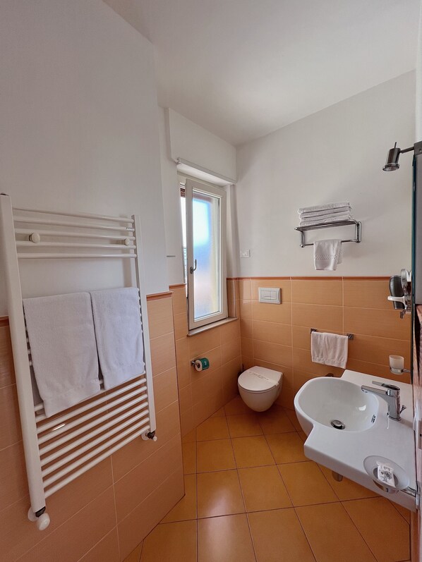 Un baño pequeño con un lavamanos blanco, un inodoro y un perchero para toallas.