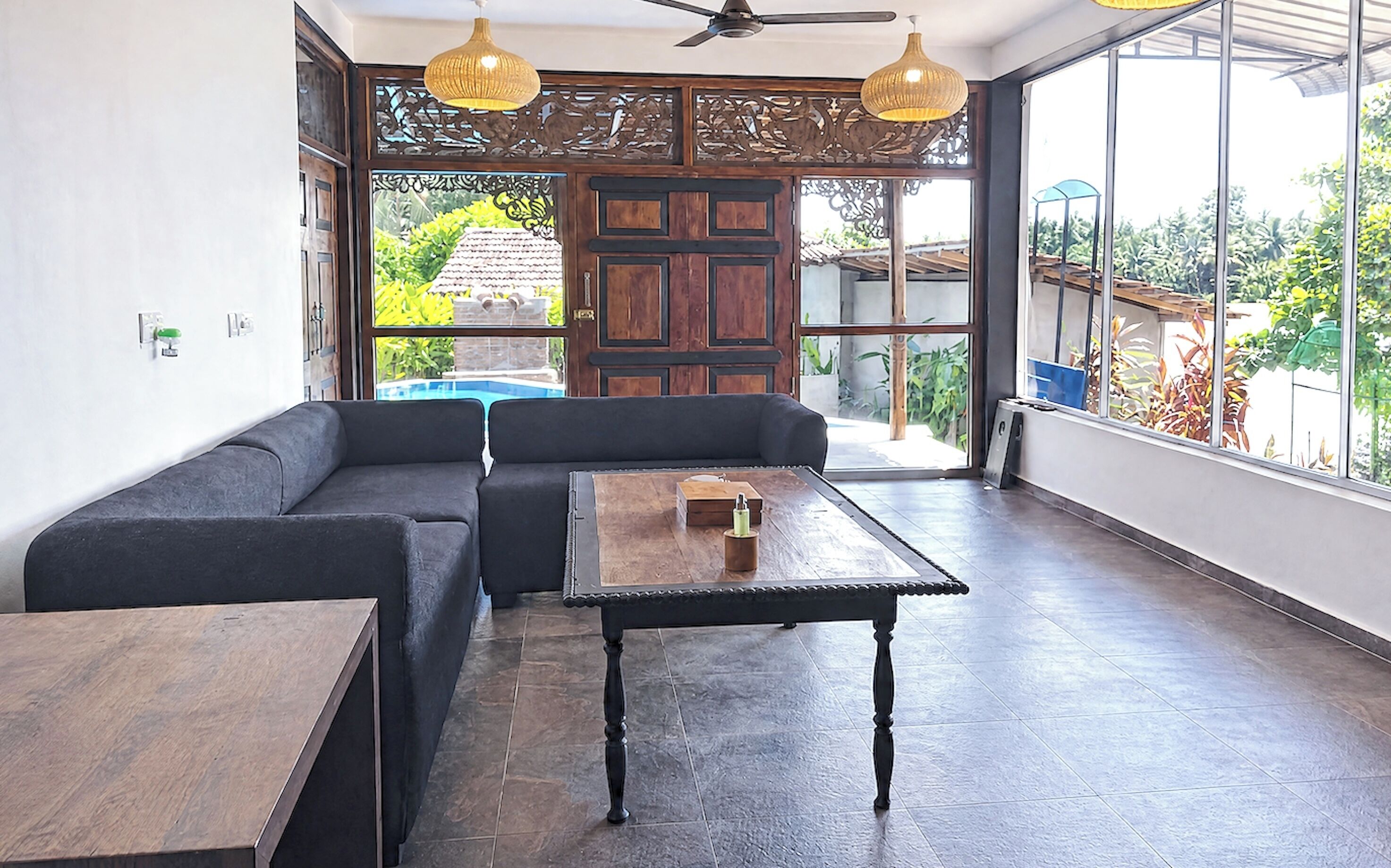 Un interior moderno con un sofá modular, una mesa de madera y ventanas amplias que dan a zonas verdes.