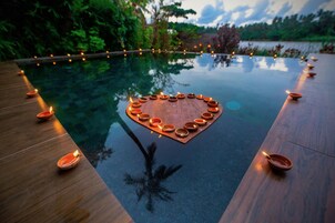 Una piscina con una disposición de velas en forma de corazón en el borde.