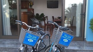 Two bicycles with baskets, parked in front of a building with a glass door and a ceiling fan visible inside. - Tra Que Riverside Homestay (Da Nang)