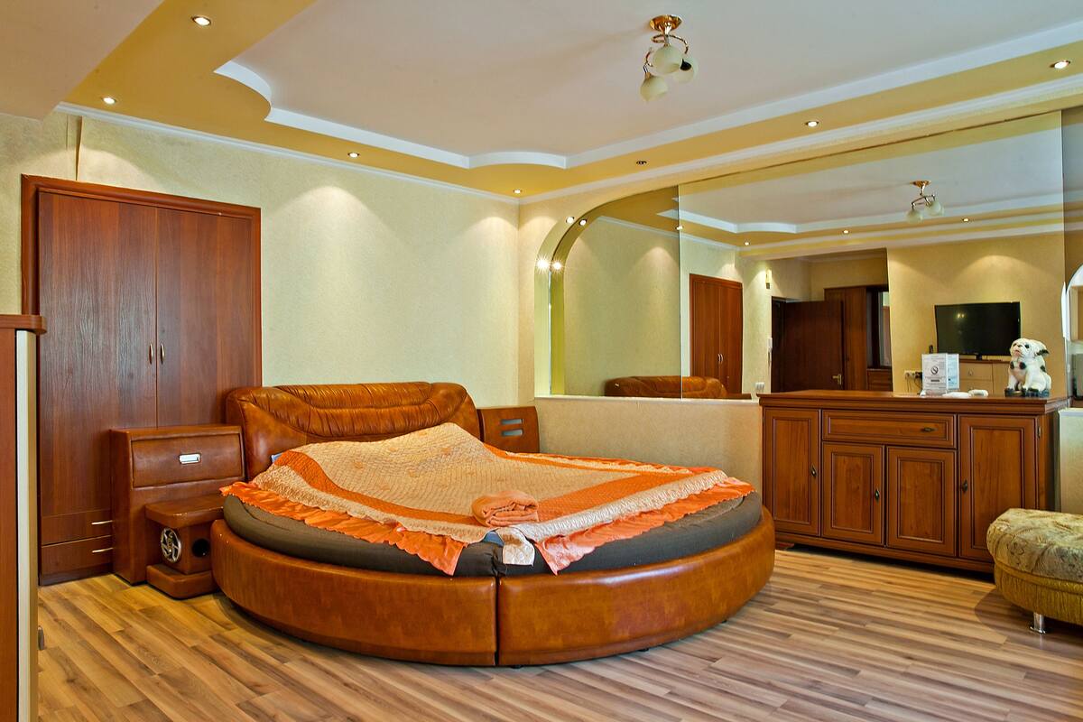 A spacious bedroom with a large bed, wooden furniture, and a mirror.