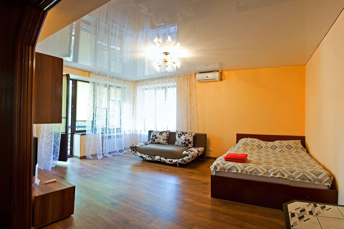 A bedroom with a bed, a sofa, and a wooden floor.