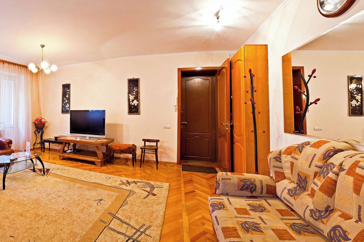A living room with a sofa, a chair, a coffee table, a TV, and a wooden cabinet.
