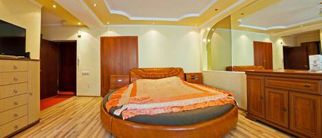 Una camera da letto ben illuminata con un letto rotondo, un'armadiatura in legno e un grande specchio.