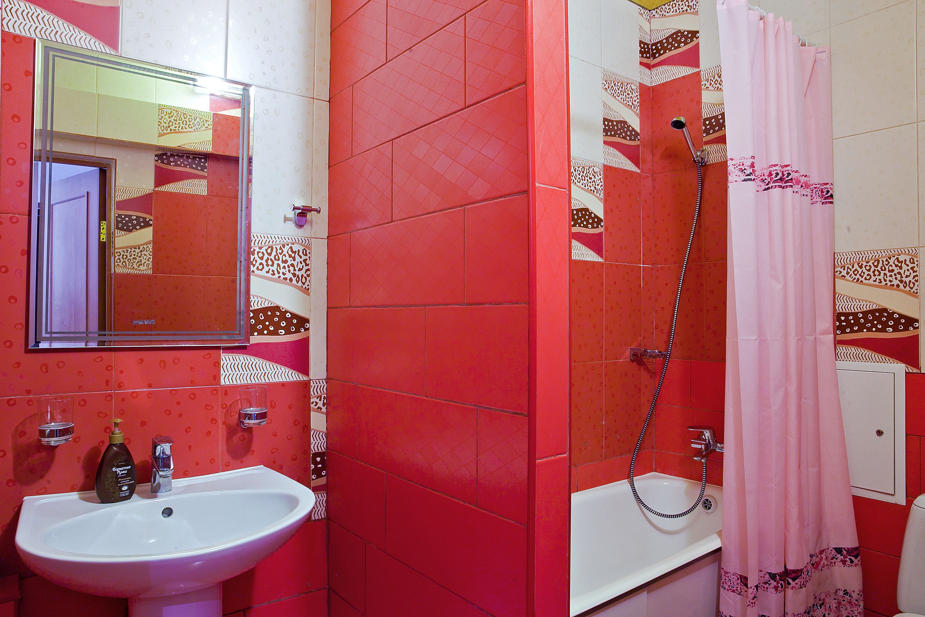 A bathroom with a sink, mirror, shower, and a pink shower curtain.