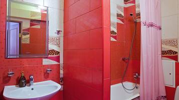 A bathroom with a sink, mirror, shower, and a pink shower curtain.