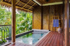 Une terrasse en bois avec une petite piscine, entourée d’une végétation luxuriante et de structures en bambou.